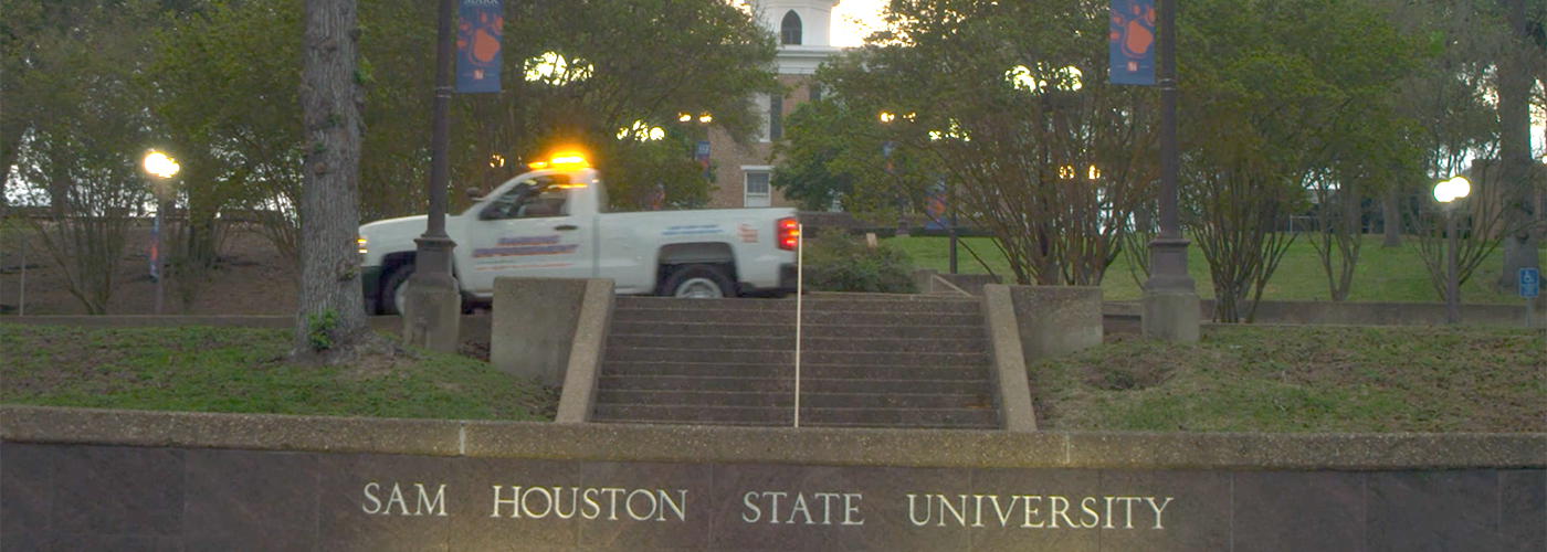 White enforcement truck passes front sign of Sam Houston State University